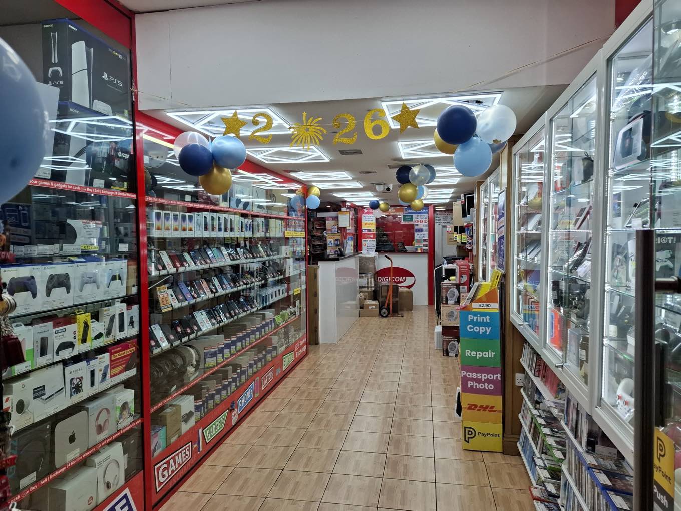 Inside DIGICOM on Whitechapel Road: cabinets of phones and consoles with a repair and passport-photo counter