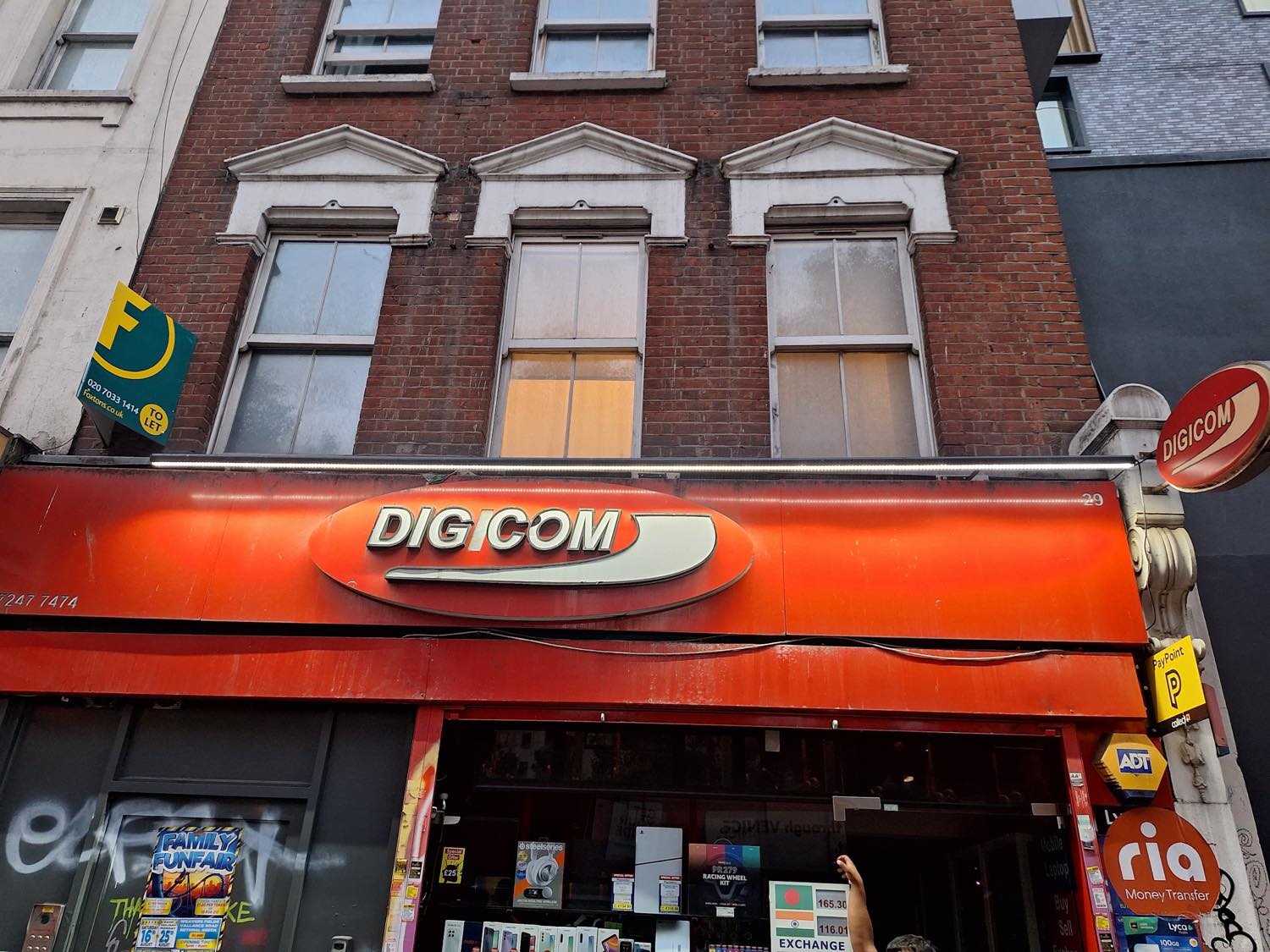 The orange DIGICOM shopfront and silver oval sign at 29 Whitechapel Road, London E1